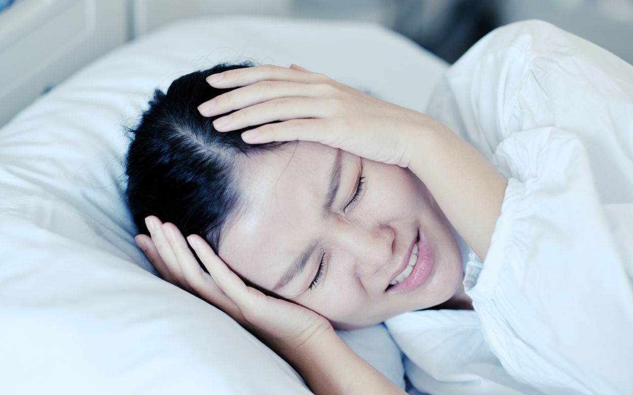 Người phụ nữ trung niên ôm đầu mệt mỏi vì mất ngủ và đau đầu kéo dài